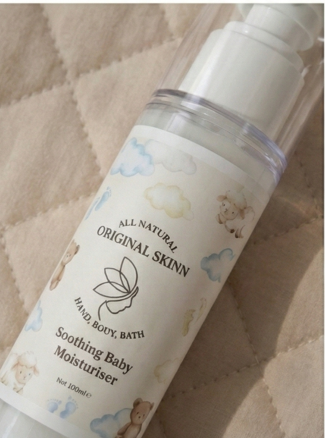 Close-up of Original Skinn Soothing Baby Moisturiser 100ml bottle on soft nursery blanket.